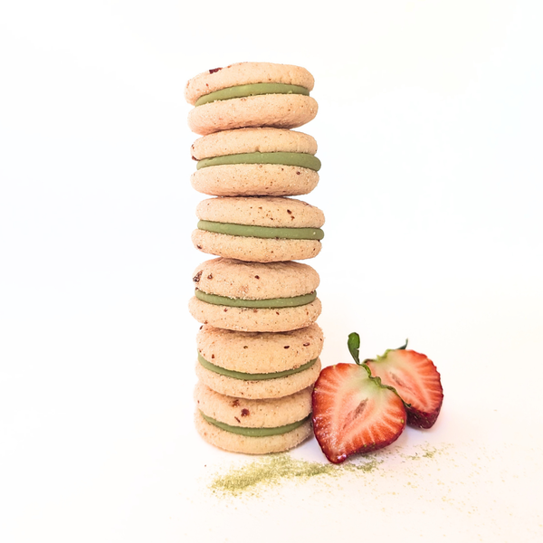 Stack of strawberry matcha cookies with a strawberry on a white background