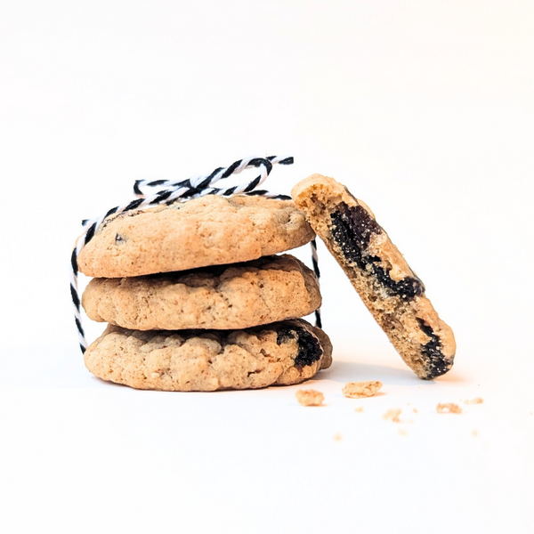 Three brown butter oatmeal raisin cookies tied with black-and-white string, with one cookie leaning against the stack on a clean white background.