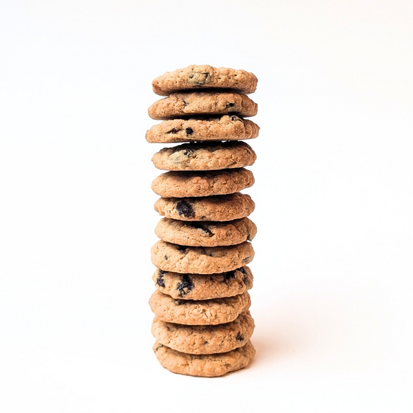 A tall stack of golden brown butter oatmeal raisin cookies stands on a white background, creating a warm, inviting, homemade dessert scene.