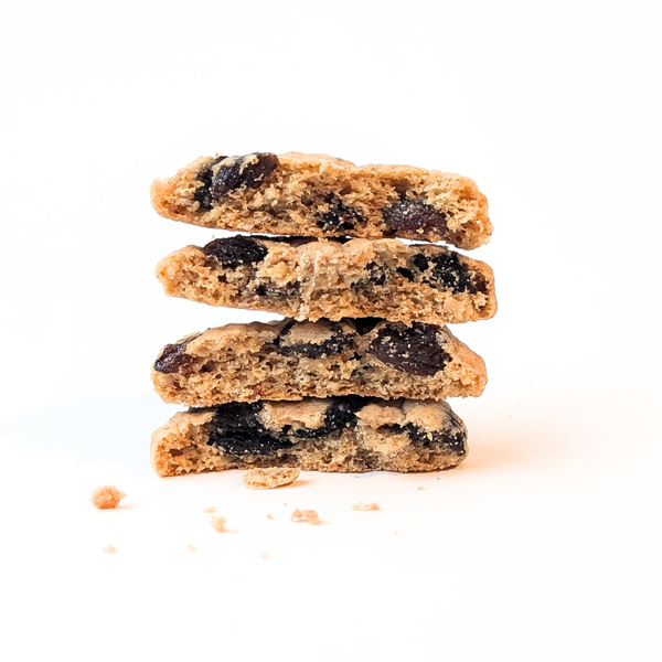 Stack of four chunky brown butter oatmeal raisin cookies with crisp edges and soft centers, isolated on white with scattered crumbs; warm, appetizing tone.