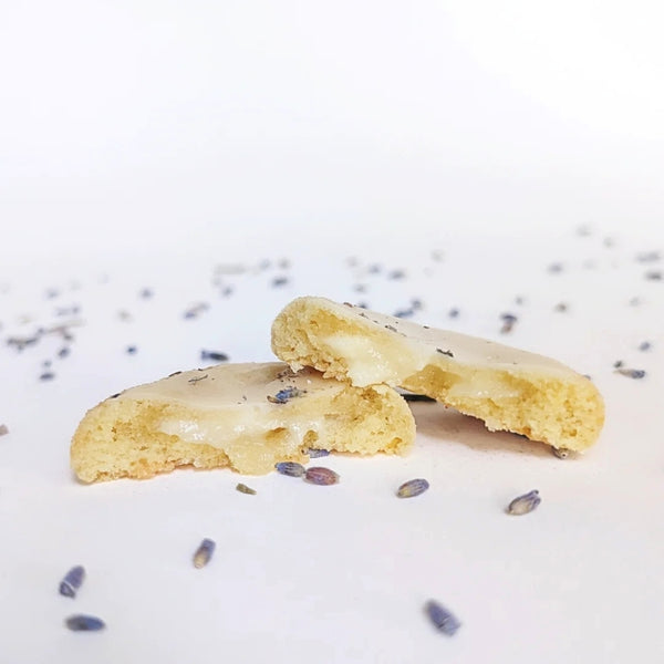 Blackout Baking Co. - Broken in half lemon cookie with lemon filling on a white surface with scattered lavender buds